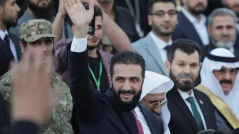 Reuters Syrian President Ahmed al-Sharaa waves amid a crowd of people