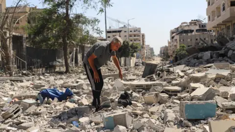 Reuters A Palestinian man inspects the damage at a residential neighborhood, following an Israeli operation in the area, after Hamas agreed to release hostages and accept some other terms in a U.S. plan to end the war, in Gaza City, October 4