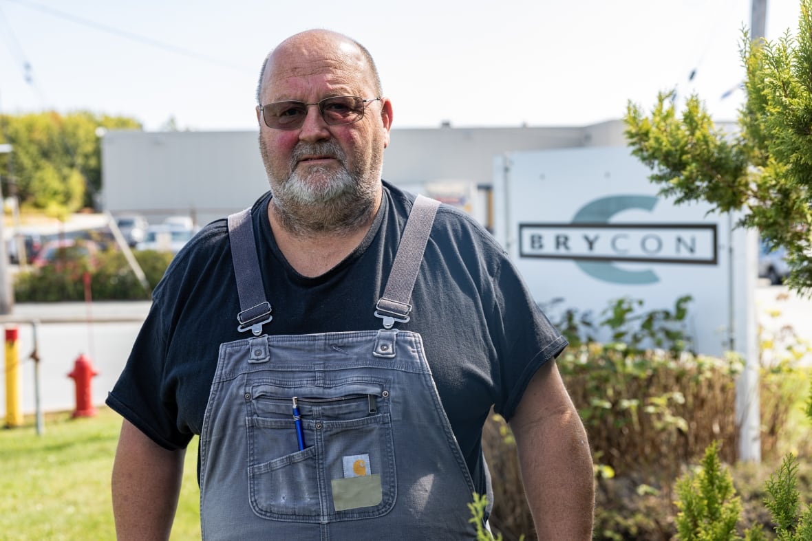 A man stands in front of a construction company. 