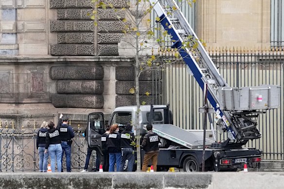 Police officers work by a basket crane used by thieves.