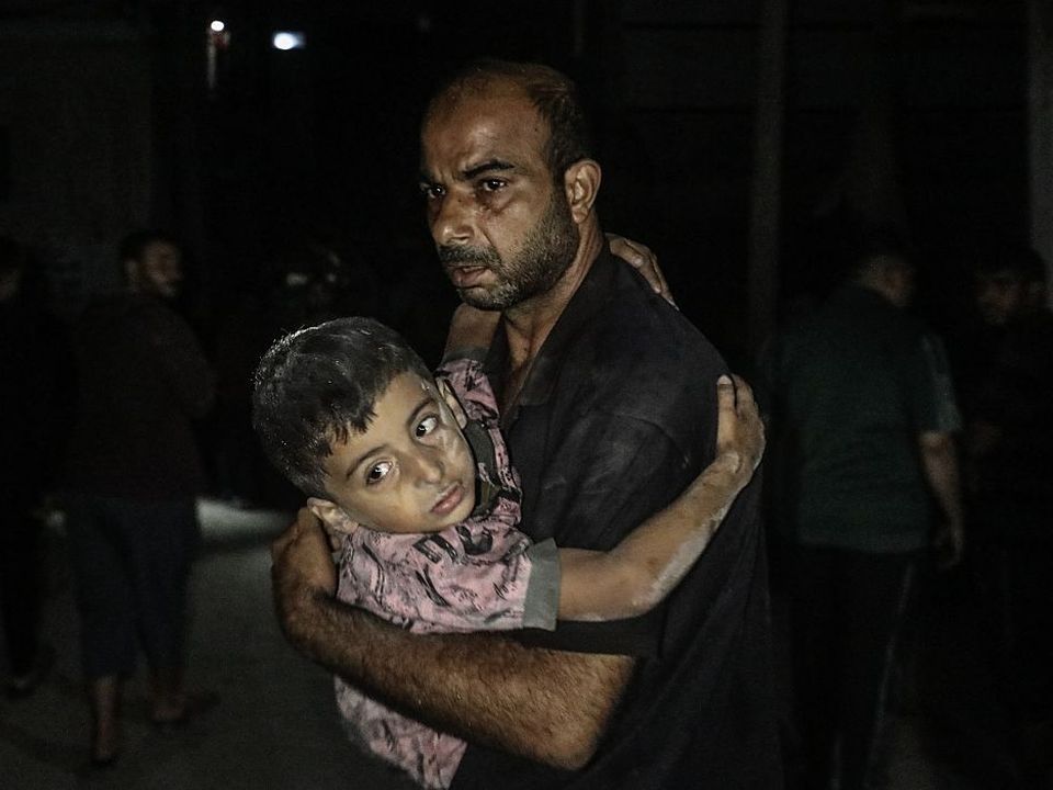 A man carries an injured child in his arms at al-Awda Hospital after Israeli strikes on the Bureij Refugee Camp in Gaza. Photo: Moiz Salhi/Anadolu via Getty.