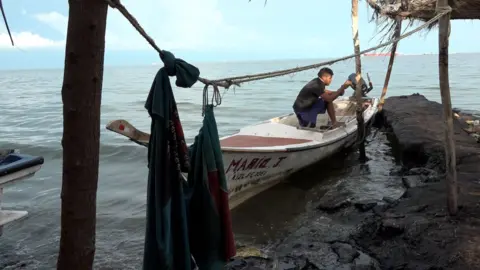Gustavo Ocando Alex Un joven en una lancha blanca amarrada en un muelle.