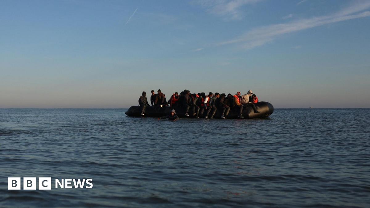 Black inflatable dinghy in the English Channel. It is filled with people.