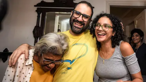 Getty Images British-Egyptian activist Alaa Abdel Fattah (C) embraces his mother, writer Laila Soueif (L), and his sister Sanaa Seif (R), at home after his release in Cairo on September 23, 2025. 