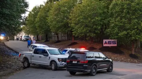 EPA/Shutterstock Police cars parked out front of the plant