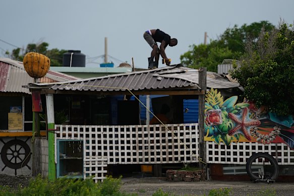 A man fortifies a roof ahead of the arrival of Melissa in Kingston.