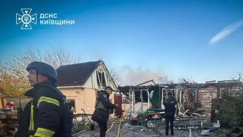 DSNS Ukraine Firefighters outside the wreckage of a burned out home near Kyiv