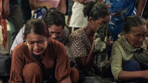 AFP via Getty Images) Women weep in front bodies not pictured in the frame during a funeral for the victims of a bombardment carried out by Myanmar's military in Mrauk U, Myanmar's Rakhine State on August 26, 2025. 