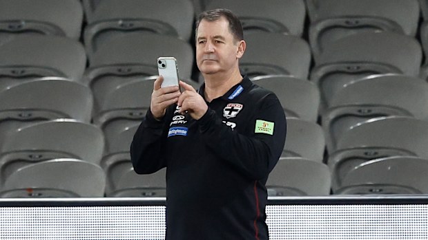 Ross Lyon, Senior Coach of the Saints is seen posting to Twitter from the wet turf.