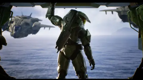 Microsoft A computer rendered image of a gaming trailer which shows a futuristic soldier in green armour looking out of the back of a airship at a body of water on an alien world.