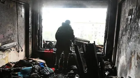 Global Images Ukraine via Getty Images A person stands amid burnt debris in an apartment damaged by a Russian drone strike on October 10, 2025 in Kyiv, Ukraine