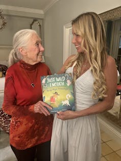 Two women face each other, smiling and holding a book