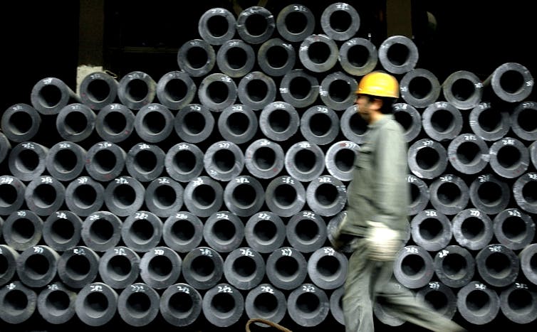 A worker walks past steel products at a steel mill in China