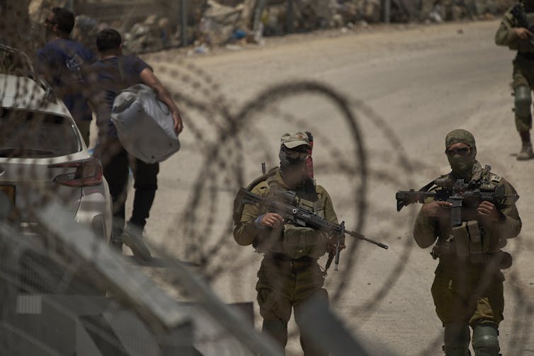 Soldiers stand by barbed-wire fences.
