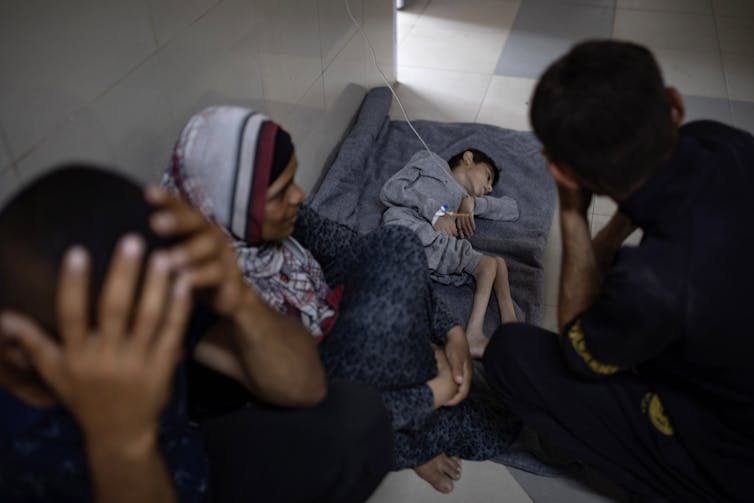 Palestinian child Younis Jumaa, suffering from malnutrition, lies on the floor over a blanket at Nasser Hospital in southern Gaza Strip in July 2024.