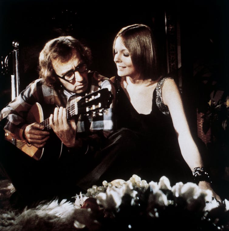 Allen plays a guitar while Keaton watches.