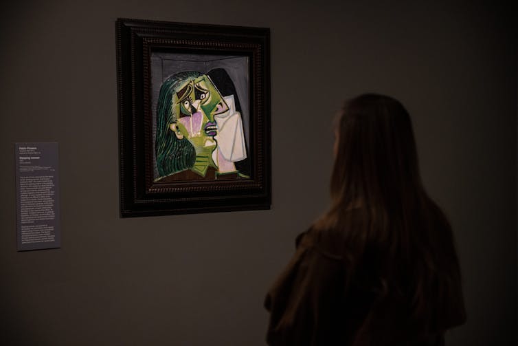 A woman stares at Weeping Woman.