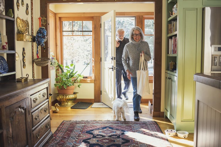 An older couple walk through the front door of their sunny home