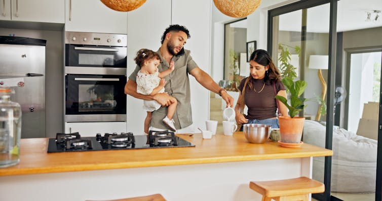 A multitasking young family making coffee in the kitchen