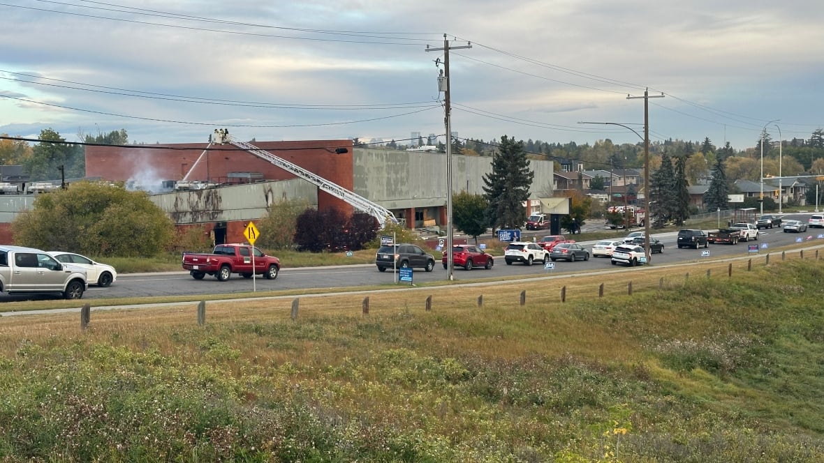 a long shot of fire crews putting water on a large building in late summer 