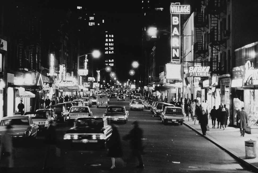 View of cars and club marquees on Eighth Street at night, looking east from Sixth Avenue in New York's Greenwich Village on November 18, 1965.