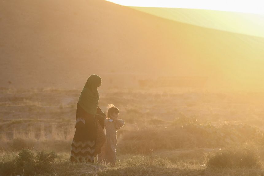 An Afghan woman and a girl walk along the Bodana Qala field in the Sholgara district of Balkh province on September 7, 2025.