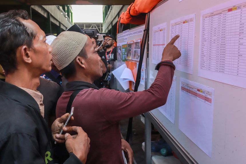 Relatives of students look at a list of names on a board as search and rescue operations continue at a boarding school in Sidoarjo on Wednesday.