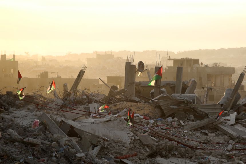 Palestinian flags flutter on top of rubble in Gaza City.