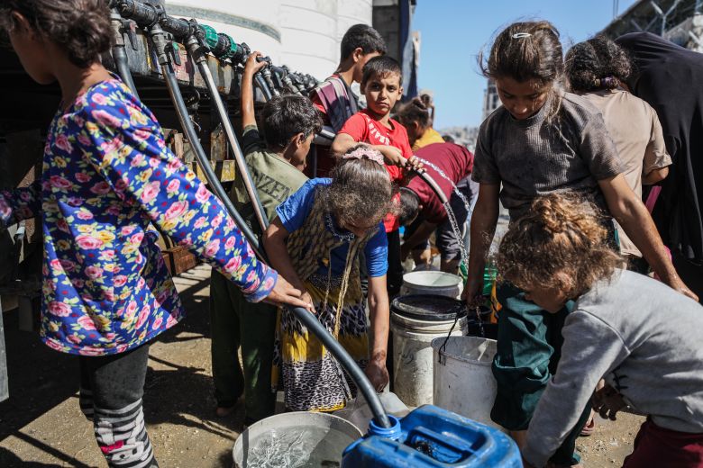 Palestinian children fill bottles with water from tanks brought in by trucks in Gaza City on Thursday.
