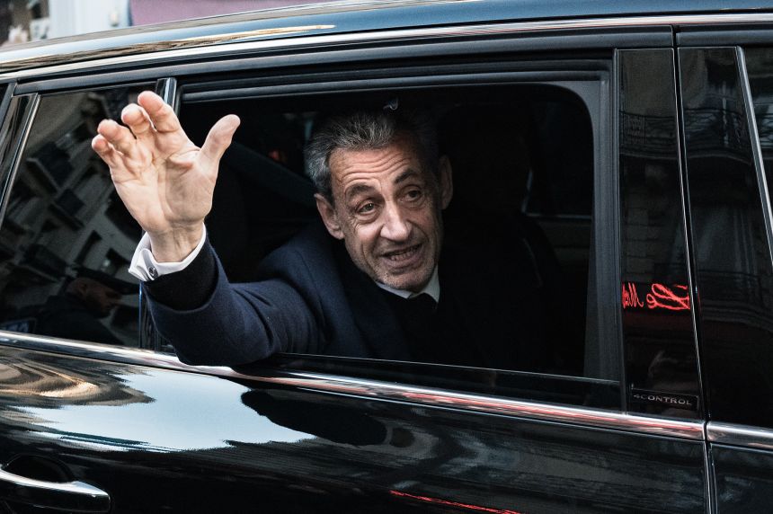 France's former president Nicolas Sarkozy waves to his supporters as he leaves his residence for prison on Tuesday.
