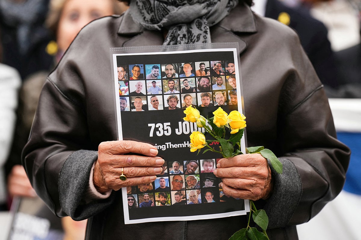 A woman holds a placards bearing the portraits of held hostages during a rally asking for the release of the hostages taken during Hamas's October 7, 2023 attack, at the Trocadero esplanade also called the Parvis des Droits de l'Homme, in central Paris, on October 10, 2025, after Israel and Hamas agreed a Gaza ceasefire deal. Israeli Prime Minister's office said on October 10 that the government had "approved the framework" of a hostage release deal with Hamas, as both sides edged closer to ending more than two years of hostilities in Gaza. The Gaza deal follows a 20-point peace plan for Gaza announced last month by US President Donald Trump, who said he planned to leave on October 12 for the Middle East. (Photo by Dimitar DILKOFF / AFP)
