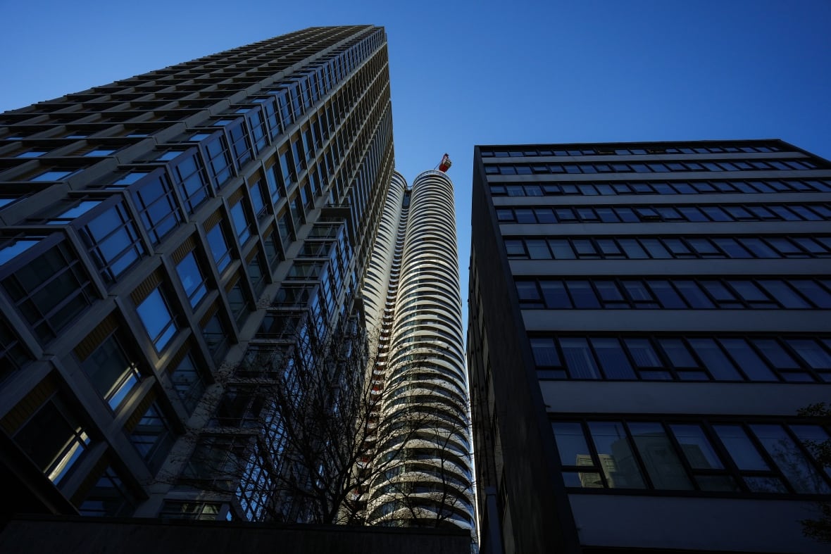 Twin building towers are seen from the ground, looking up.
