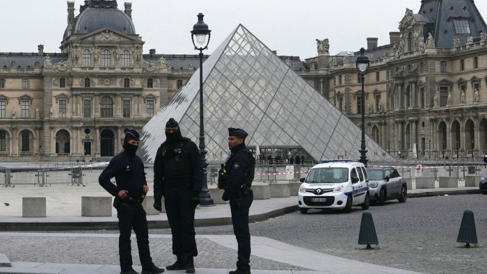 French police officers stand in front of the Louvre in Paris