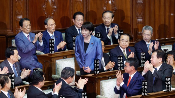 Sanae Takaichi stands and acknowledges applause from fellow lawmakers after being elected Japan's first female prime minister.