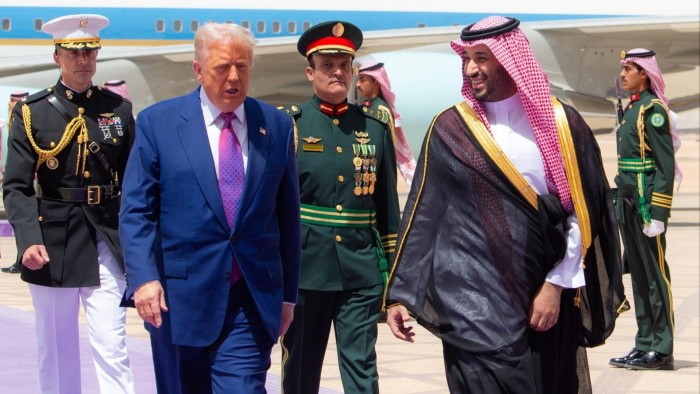 Donald Trump is greeted by Saudi Crown Prince Mohammed bin Salman Al Saud at an airport, with military personnel nearby.