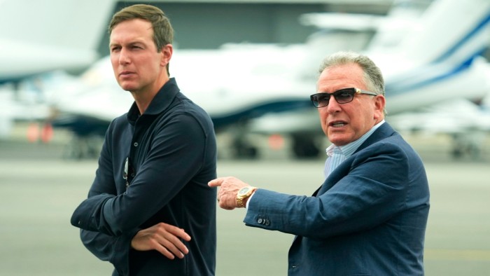 Steve Witkoff, wearing sunglasses and gesturing, stands beside Jared Kushner as they wait on the tarmac near private jets.
