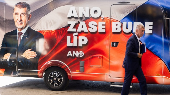 Andrej Babis walks past a campaign vehicle featuring his portrait and the slogan "ANO, ZASE BUDE LÍP" during an election rally.