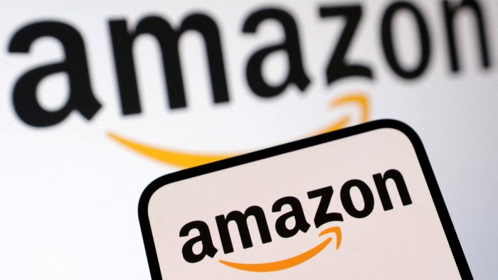 The Amazon logo is displayed on a smartphone screen in front of a blurred larger version of the logo.