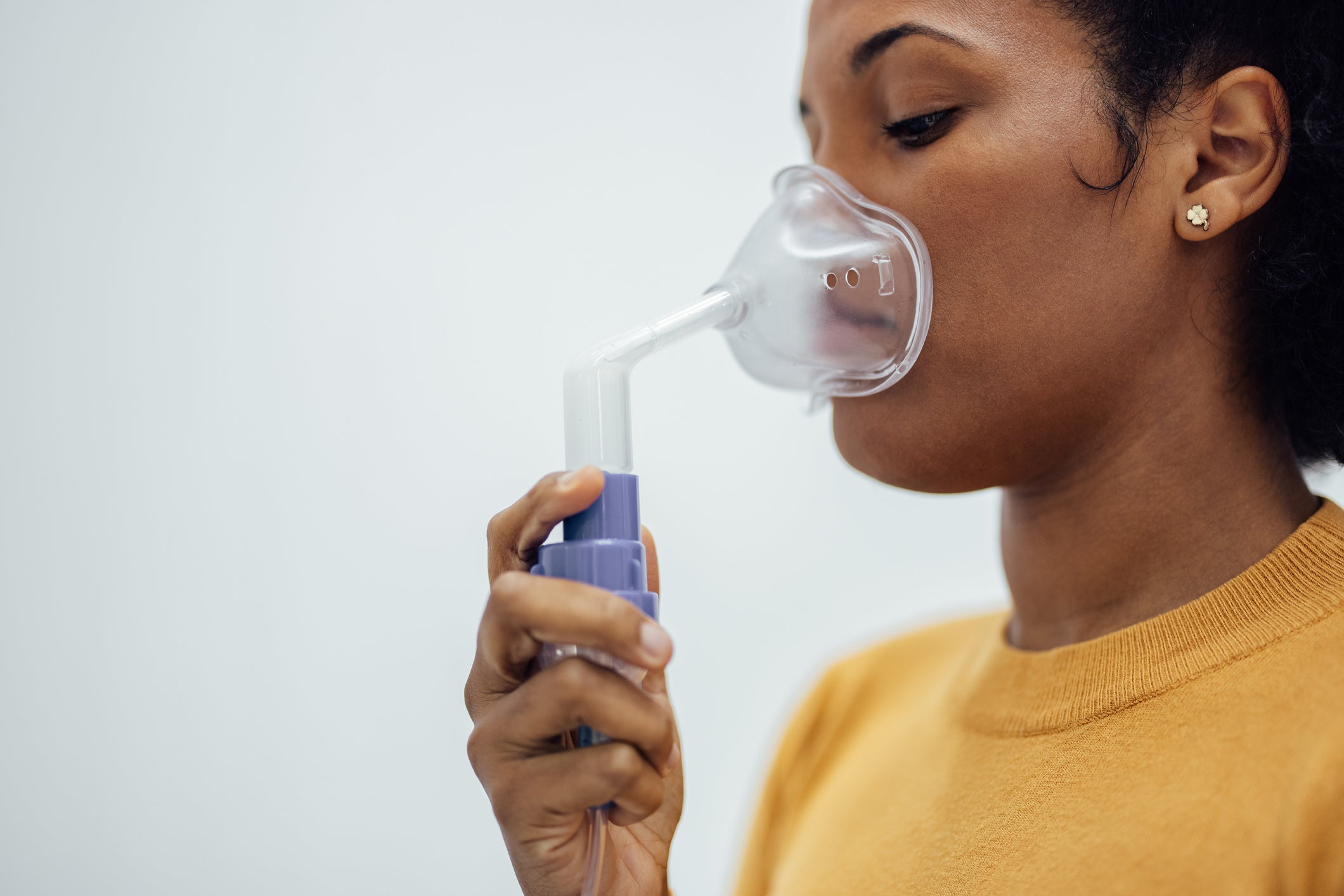 Close-up of a woman holding respiratory mask. Using nebulizer.