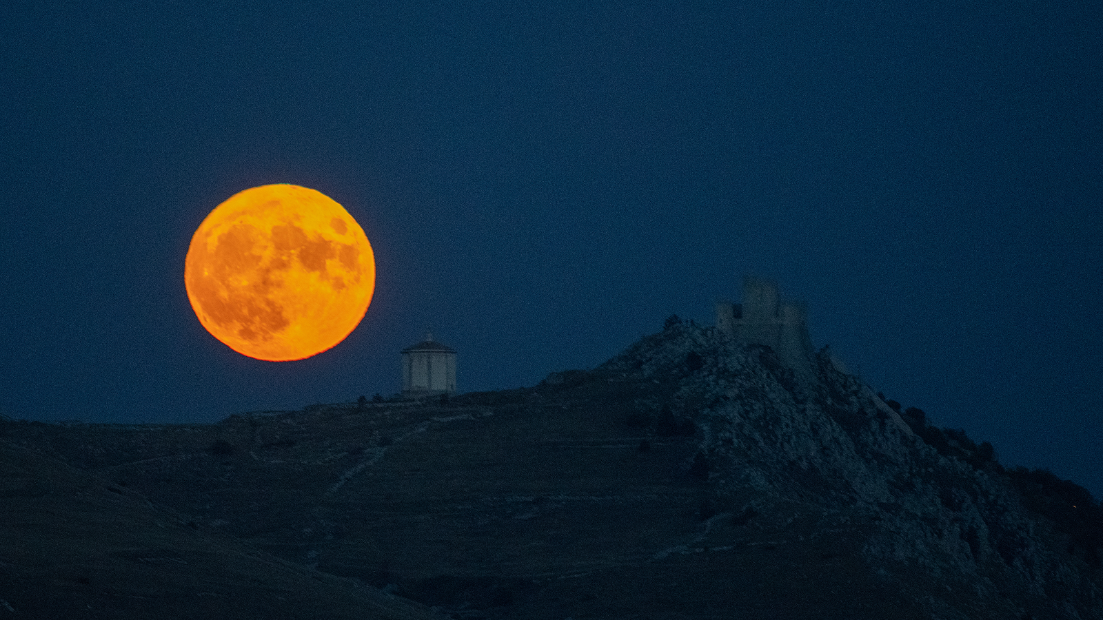 Harvest moon shining behind Rocca Calascio Castle, Abruzzo, Italy on October 1, 2020.