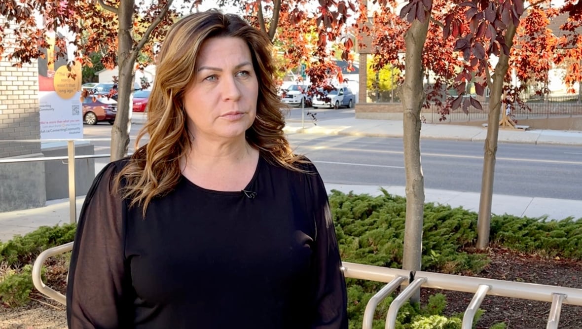 A woman with brown hair stands in front of a street.