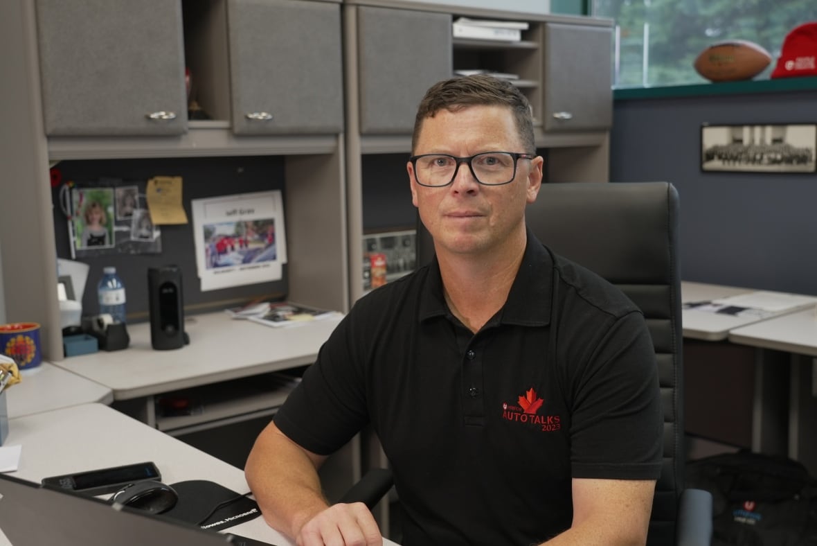 Photo of a man in a black t-shirt sitting at a desk 