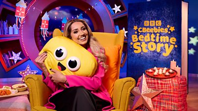 Photo of Nikita Kanda in the CBeebies Bedtime Stories. She hugs the yellow CBeebies Bedtime Stories mascot. 