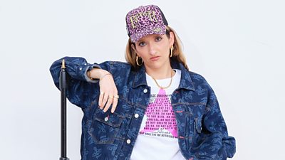 Headshot of Saint Ludo, leaning on a microphone stand. 