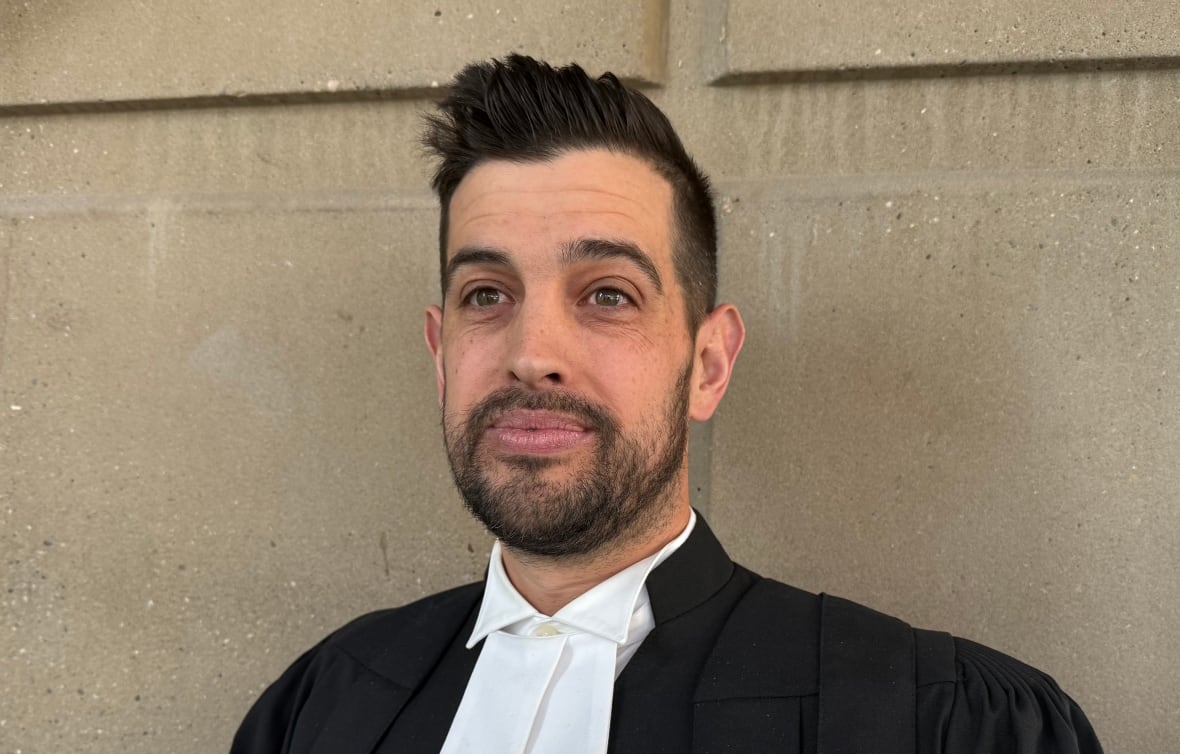 A man in his court attire stands in the courthouse lobby. 