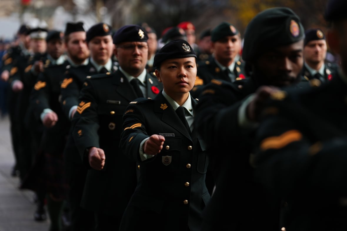 Military members march during a war memorial ceremony in autumn.