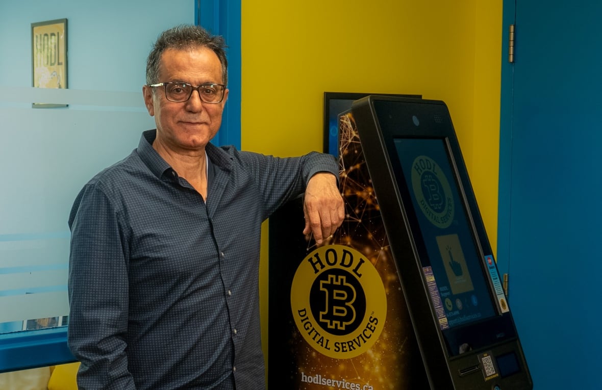 Man standing beside a cryptocurrency ATM.