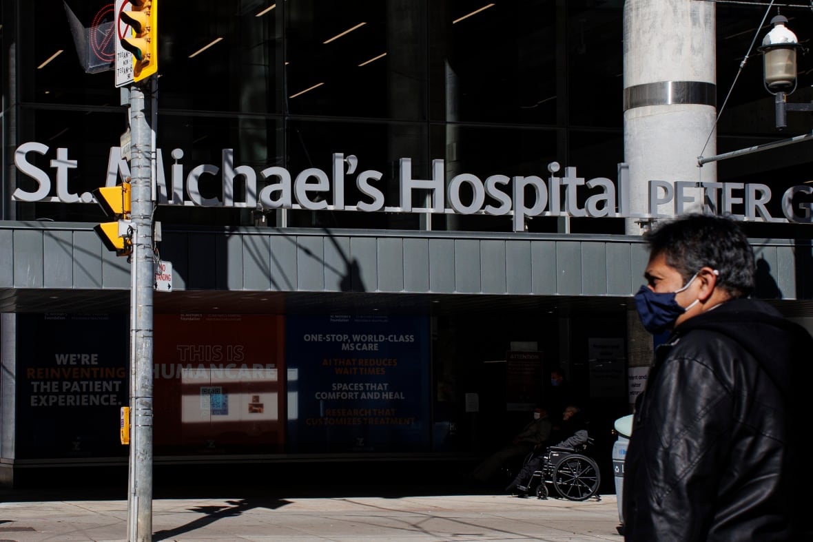 a downtown city street with the hospital in the background, name sign visible
