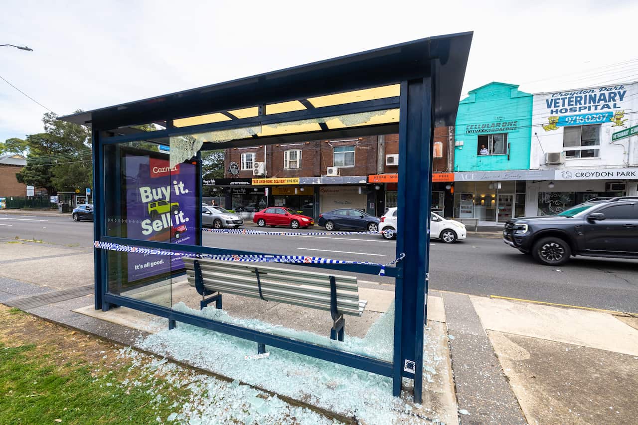 Rear view of a bus stop with shattered glass below it