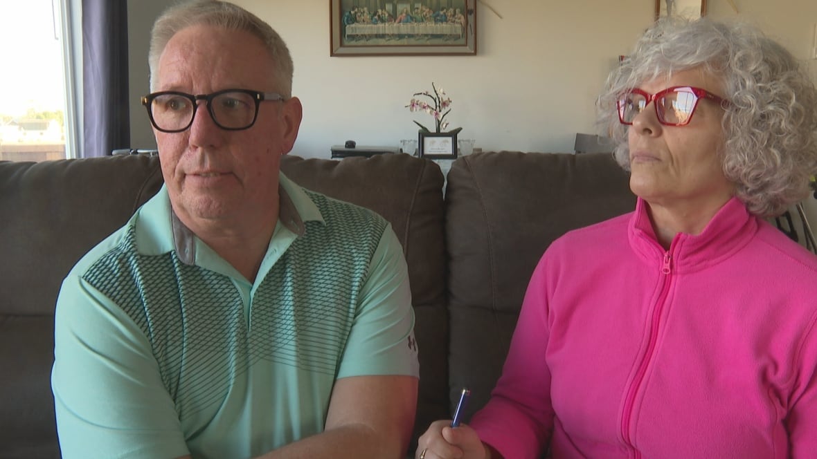 A man in a pale green golf shirt and a woman in a bright pink fleece jacket.